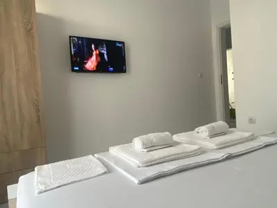 a room with three towels and a tv on the wall at Апартамент Узунови in Sandanski