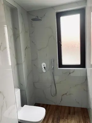 a bathroom with a shower with a toilet and a window at Апартамент Узунови in Sandanski