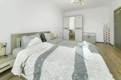 a white bedroom with a large bed with a gray blanket at Nova #7 in Sofia