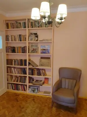 a chair in front of a book shelf with books at Apartment Lozenetz in Sofia