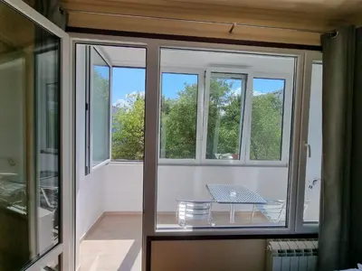 a room with windows and a table on a balcony at Apartment's Ortakchiev 2 in Sofia