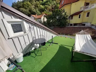 a balcony with green grass and a table and chairs at Musala 1 Bed & Breakfast in Kyustendil