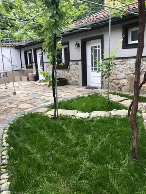 a house with a yard with trees in front of it at Musala 1 Bed & Breakfast in Kyustendil