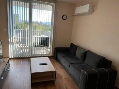 a living room with a couch and a large window at Апартамент Комфорт, близо до Летището in Sofia
