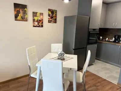 a kitchen with a table and chairs and a refrigerator at Апартамент Комфорт, близо до Летището in Sofia