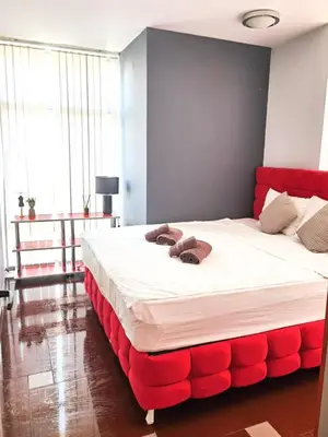 a bedroom with a large bed with red padding at Boutique Apartment in Plovdiv