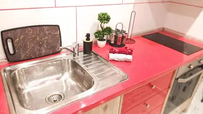 a kitchen sink with a red counter top at Boutique Apartment in Plovdiv
