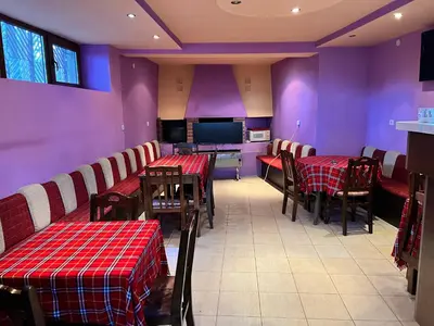 a restaurant with tables and chairs and purple walls at Почивна база Пиринпласт in Gotse Delchev