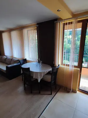 a living room with a table and chairs and a couch at Апартамент Родопи in Smolyan
