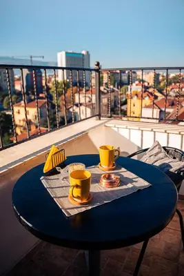a table on a balcony with two yellow cups and a table with a view at Pumpkin Spiced Suite with Own Parking and Office Setup in Sofia