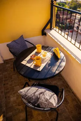 a table with two cups and a plate of food on a balcony at Pumpkin Spiced Suite with Own Parking and Office Setup in Sofia