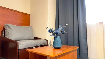 a blue vase with flowers on a table next to a chair at Dezudava Family Hotel in Sandanski