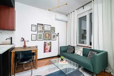 a living room with a green couch and a television at Central Art-Inspired Flat with Private Garage in Sofia