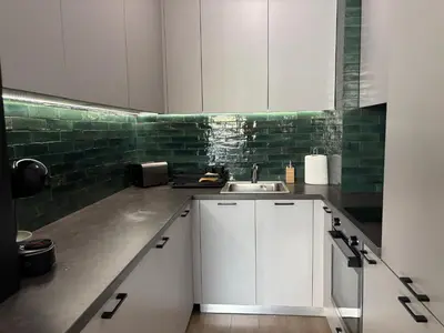 a kitchen with white cabinets and green tiles at Madrid: A modern 2-bedroom apartment with parking in Sofia