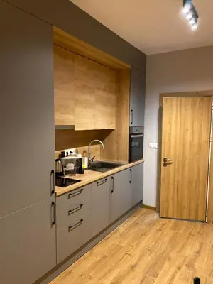 a kitchen with white cabinets and a wooden floor at Urban Elegance by Eagles' Bridge in Sofia
