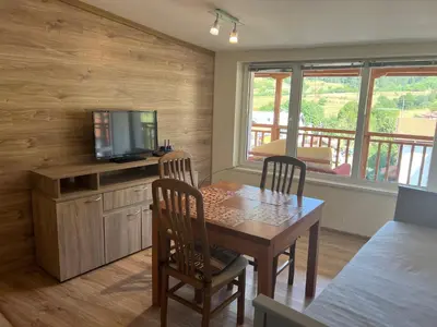 a dining room with a table with two chairs and a television at Alpine Nest: 6km to ski slopes in Beli Iskar