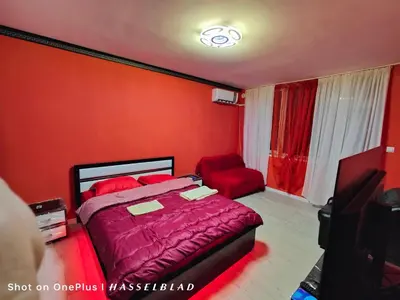 a bedroom with red walls and a bed and a chair at Тристаен апартамент в центъра in Sofia