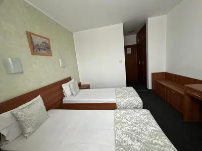 a hotel room with two beds and a desk at Family Hotel 007 Ivan Dimitrov-Kuklata 15 Str in Sofia