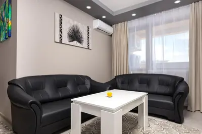 a living room with two black leather couches and a white table at Comfy Apartment with Private Parking in Plovdiv
