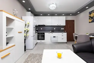 a kitchen with white cabinets and a table at Comfy Apartment with Private Parking in Plovdiv