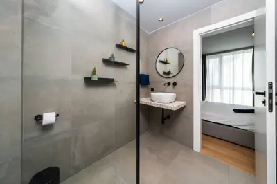 a bathroom with a shower and a sink and a mirror at Vitosha Apartment With Parking in Sofia