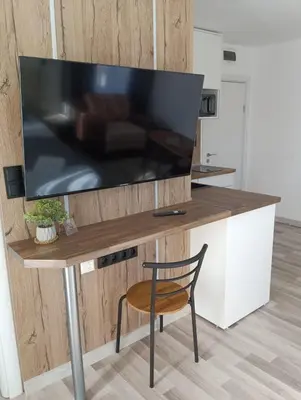 a large flat screen tv on a wooden table with a chair at Monfort A in Bansko