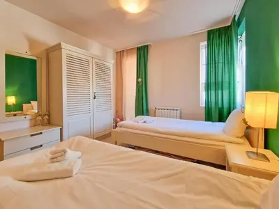 a bedroom with two beds and a window with green curtains at Bansko Royal Towers - 2BD Flat with Parking by Flat Mаnager in Bansko