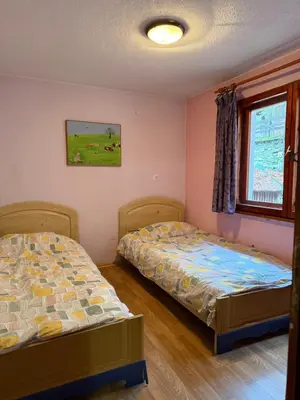 a bedroom with two beds and a window at Вила за гости “Попина лъка” in Vikhren