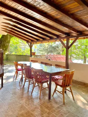 a table and chairs under a wooden pergola at Вила за гости “Попина лъка” in Vikhren