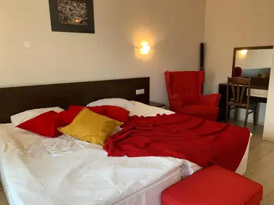 a bed with red and yellow pillows and a red chair at Banderitsa Apartment 1 in Bansko