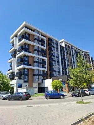 a large apartment building with cars parked in a parking lot at Студио Ели - Пловдив in Plovdiv