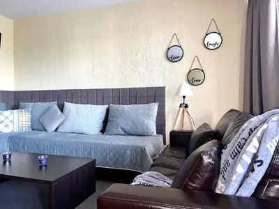 a living room with a couch and clocks on the wall at Private Suite at Comfort Bansko in Bansko