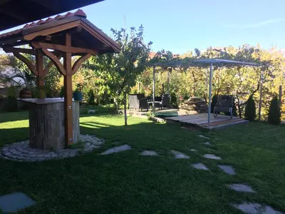 a wooden gazebo in a yard with a bench at Slavina Guest House in Sapareva Banya