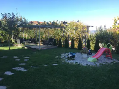 a backyard with a playground with a slide in the grass at Slavina Guest House in Sapareva Banya