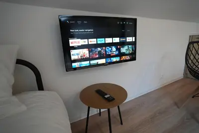 a tv on a wall with a remote control on a table at Lily's Studio 1 by Bulgarentals - Central Sofia in Sofia
