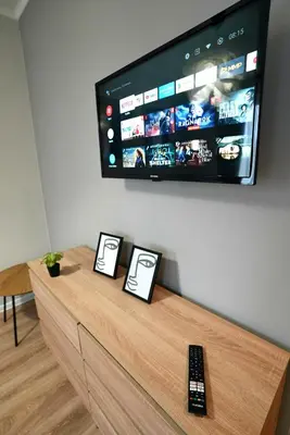 a flat screen tv on a wall with two remote controls at Lily's Studio 4 by Bulgarentals - Central Sofia in Sofia