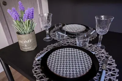 a black table with plates and glasses and a vase with purple flowers at Lily's Studio 7 by Bulgarentals - Central Sofia in Sofia