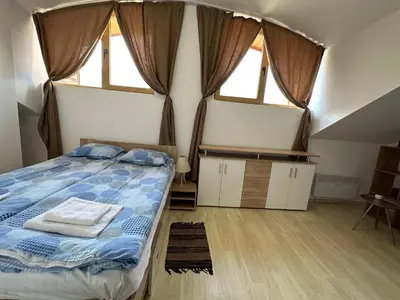 a bedroom with a bed and two windows at Cozy duplex apartment in St. John Park in Bansko