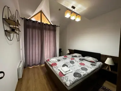 a bedroom with a bed with a flowered blanket and a window at Cozy duplex apartment in St. John Park in Bansko