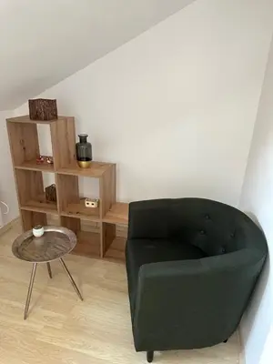 a living room with a green chair and a table at Cozy duplex apartment in St. John Park in Bansko