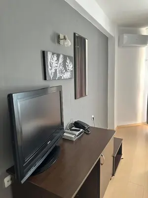 a living room with a flat screen tv on a table at Хотел Костенец in Kostenets Village