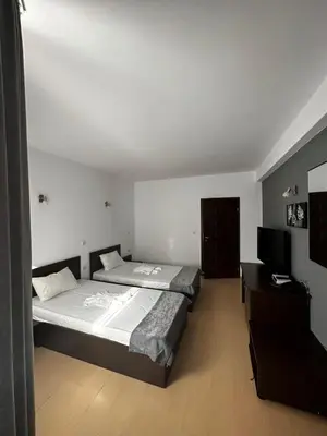 a bedroom with two beds and a flat screen tv at Хотел Костенец in Kostenets Village