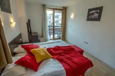 a bed with a red and yellow blanket on it at Banderitsa Studio Bansko 2 in Bansko