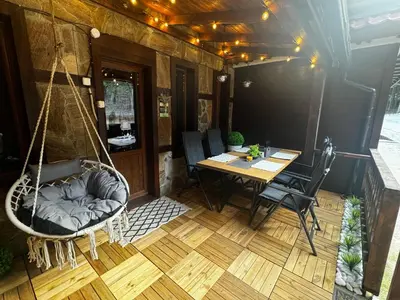 a porch with a swing and a table and chairs at Avelov Art Studio in Pamporovo