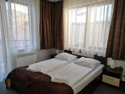 a bedroom with a large bed with two windows at апартаменти Уют Гранд Манастира in Pamporovo