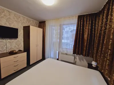 a bedroom with a bed and a dresser and a window at апартаменти Уют Гранд Манастира in Pamporovo