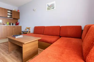 a living room with a red couch and a table at One bedroom apartment in Hotel Banderitsa ,Bansko in Bansko