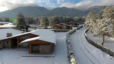 a house covered in snow next to a road at Pirin Golf Guest Room in Razlog