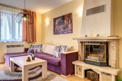 a living room with a purple couch and a fireplace at 1BD Ski View Retreat in Pamporovo with Fireplace by Flat Mаnager in Pamporovo