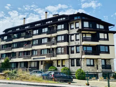 a large building with cars parked in front of it at Studio El - All seasons in Bansko